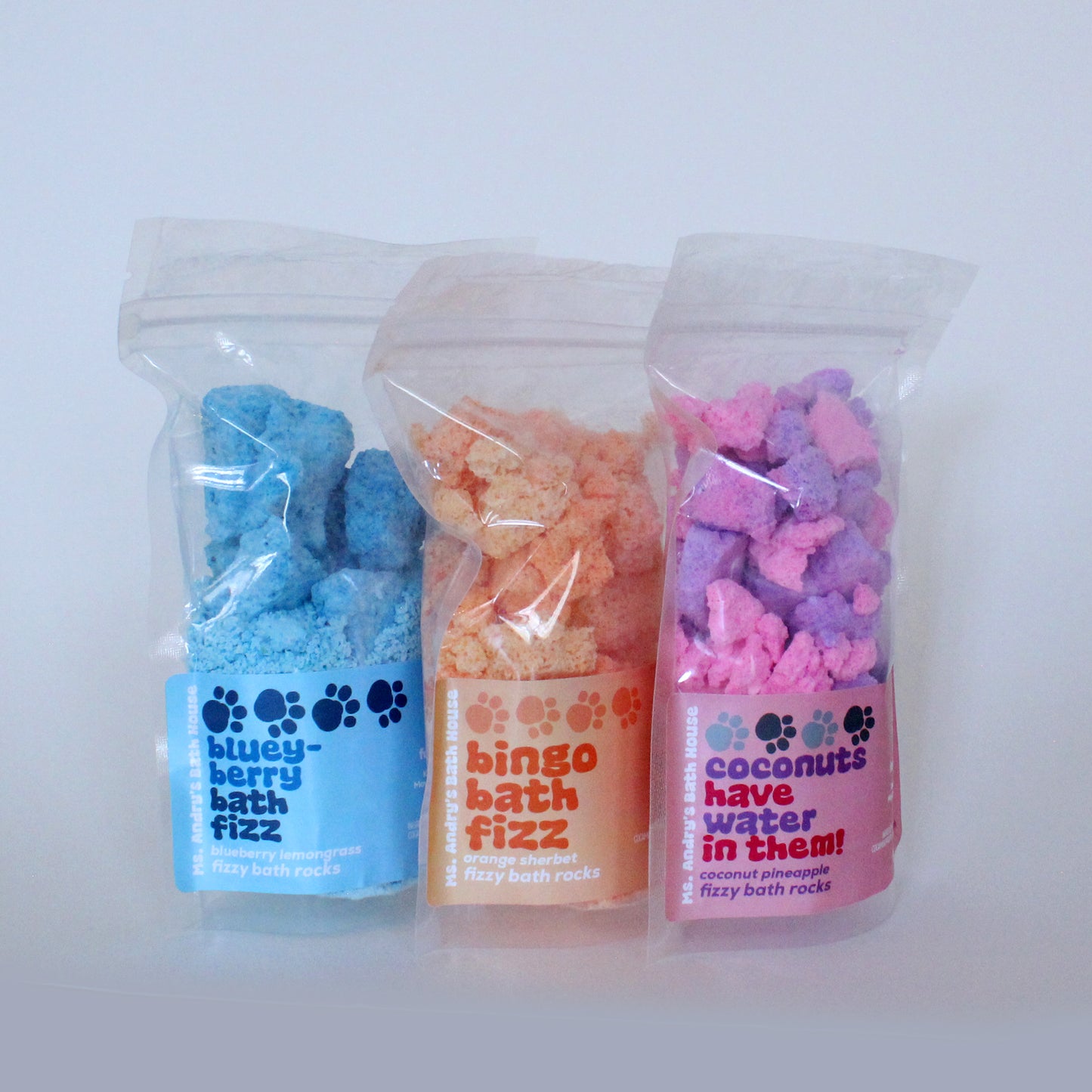 Three packages of bath fizz products with colorful packaging on a white background