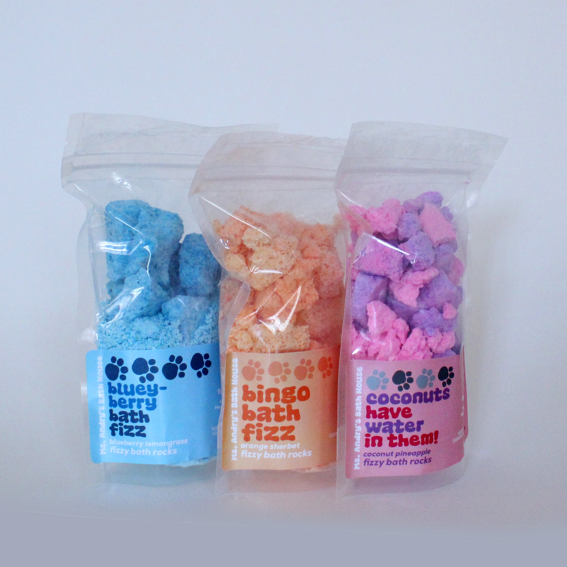 Three packages of bath fizz products with colorful packaging on a white background